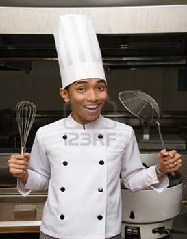 Description: Young male smiling Chinese cook or chef proudly showing kitchen utensils in the kitchen of a large hotel restaurant.